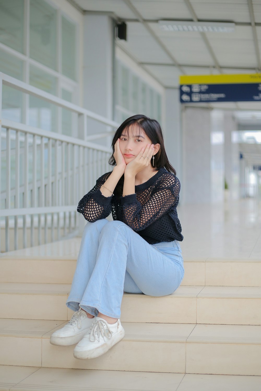 Eine Frau sitzt auf den Stufen eines Flughafens
