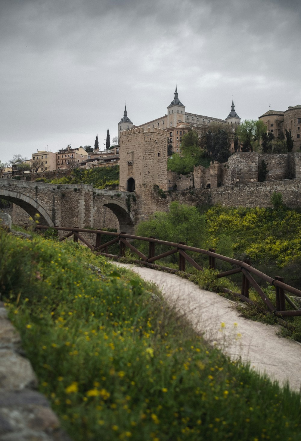 a stone bridge over a river next to a lush green hillside