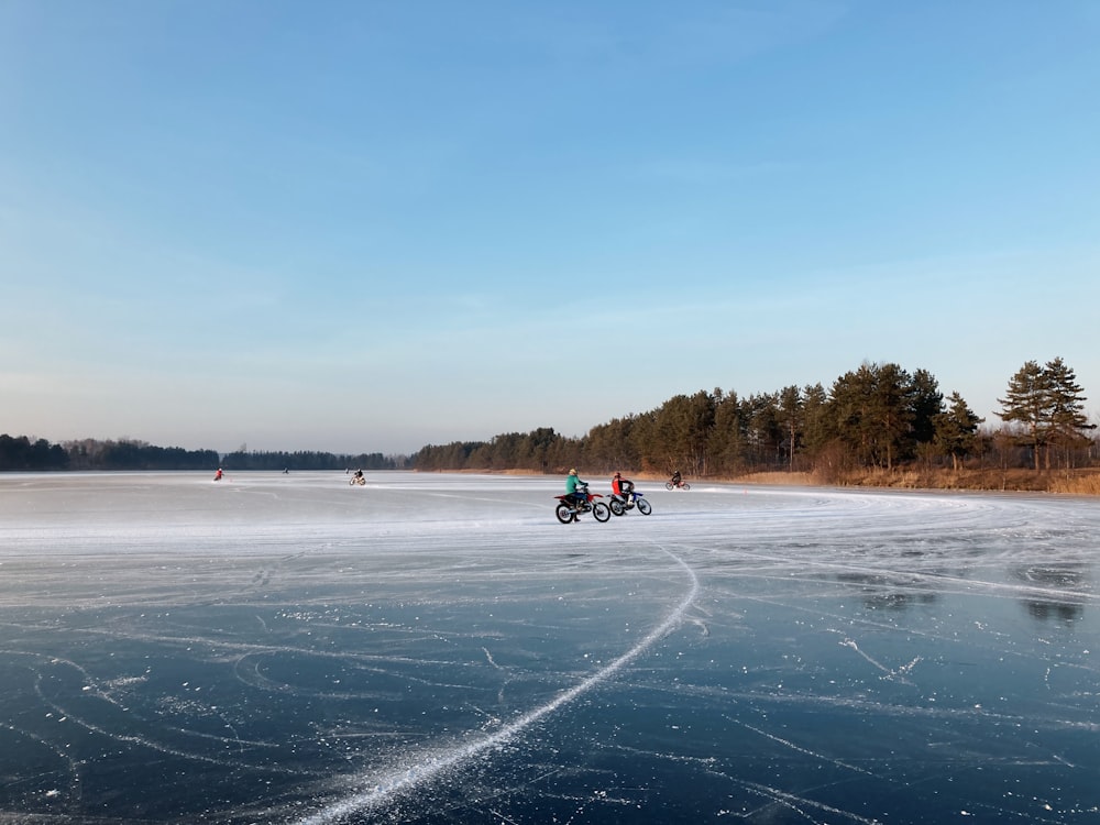 a couple of people riding motorcycles on a frozen lake