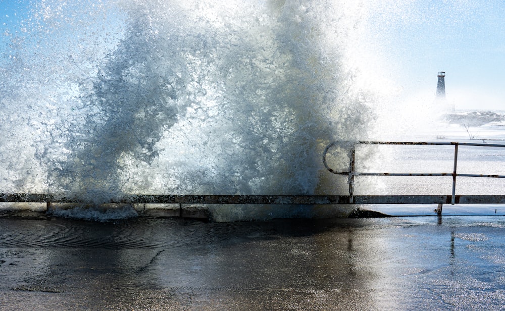 a large wave crashing over a metal railing