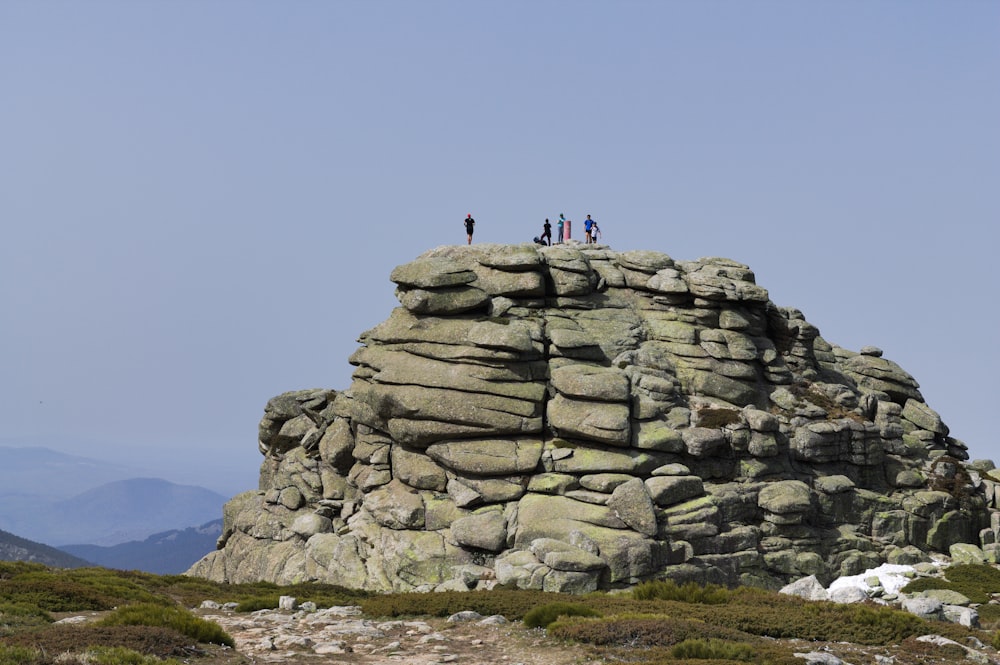 a group of people standing on top of a large rock