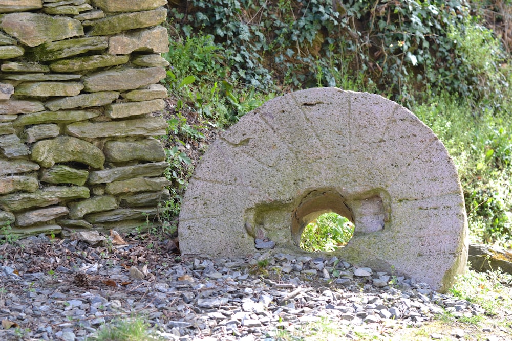 a stone sculpture sitting next to a stone wall