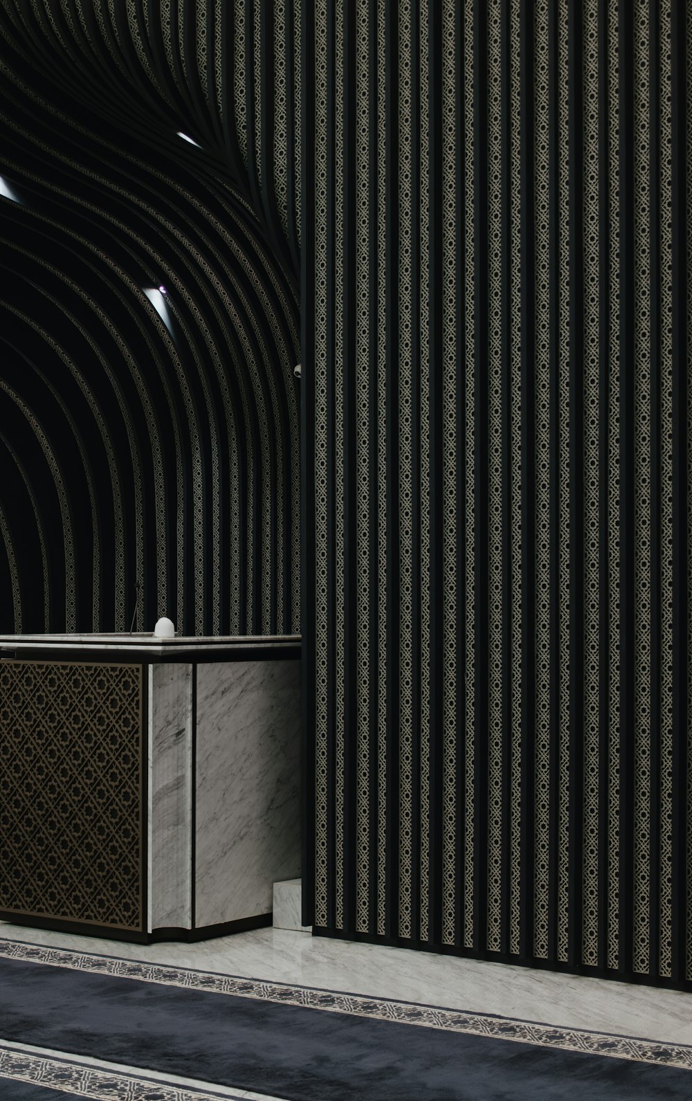 a black and white striped wall with a white cabinet