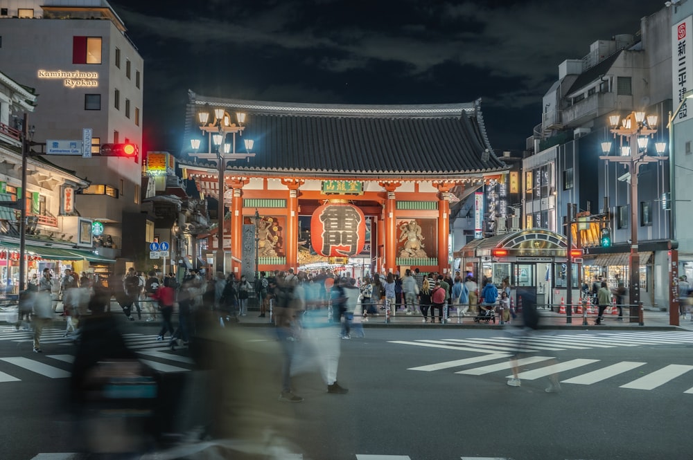 a crowd of people walking across a street at night