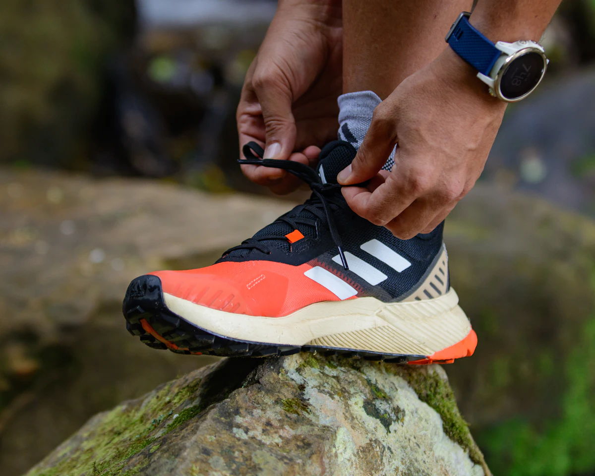 Un coureur lace ses chaussures de trail sur un rocher
