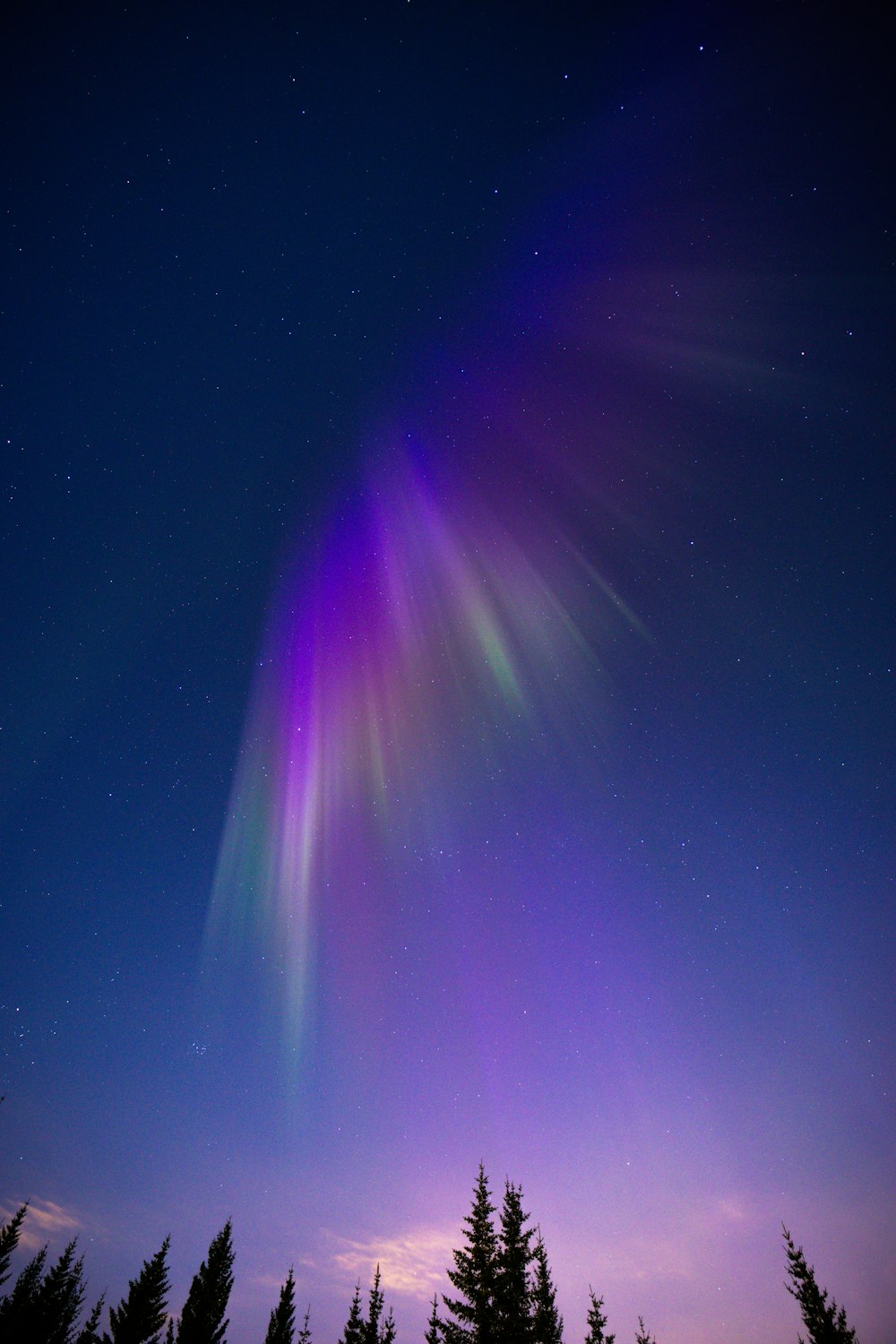 a bright purple and green aurora bore in the night sky