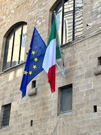 two flags are flying in front of a building