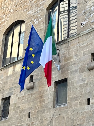 two flags are flying in front of a building