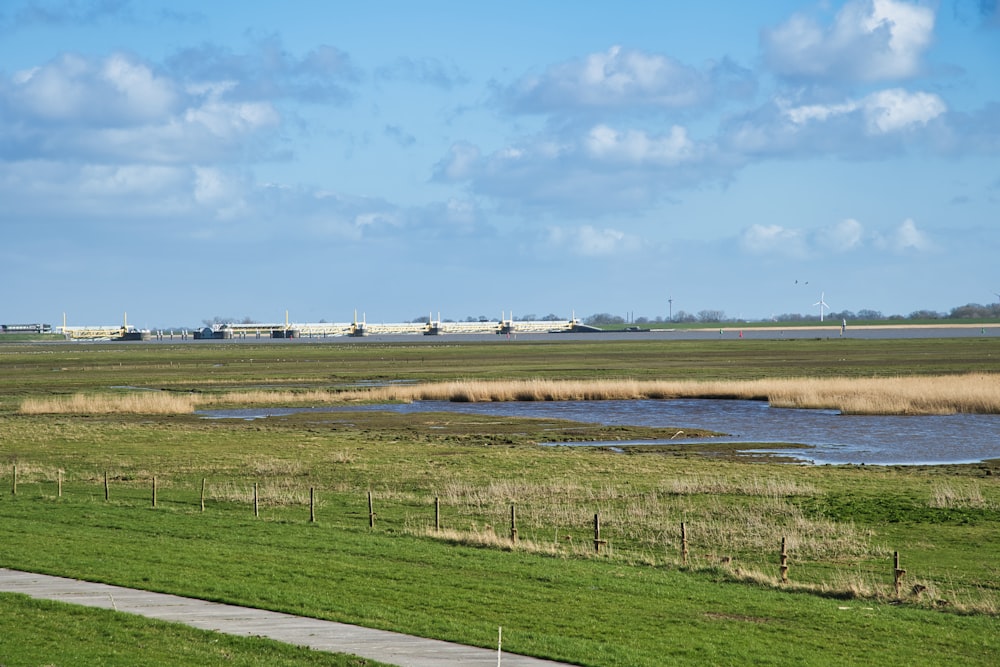 a grassy field with a body of water in the foreground