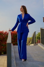 a woman in a blue suit standing on a ledge