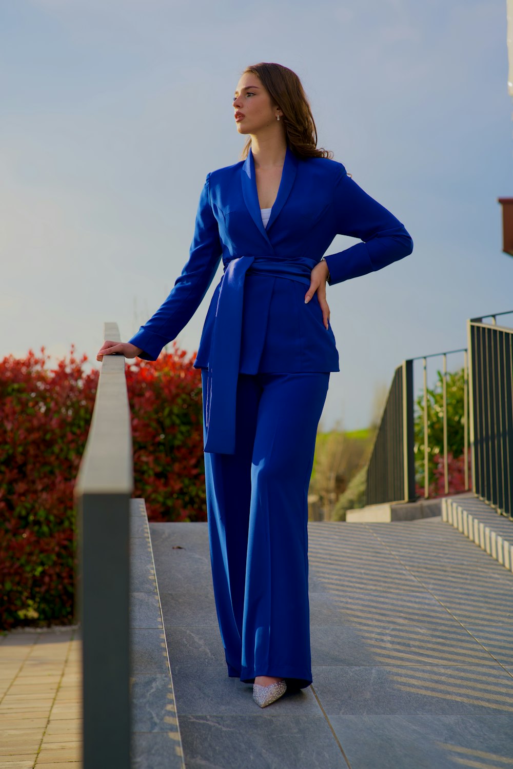a woman in a blue suit standing on a ledge
