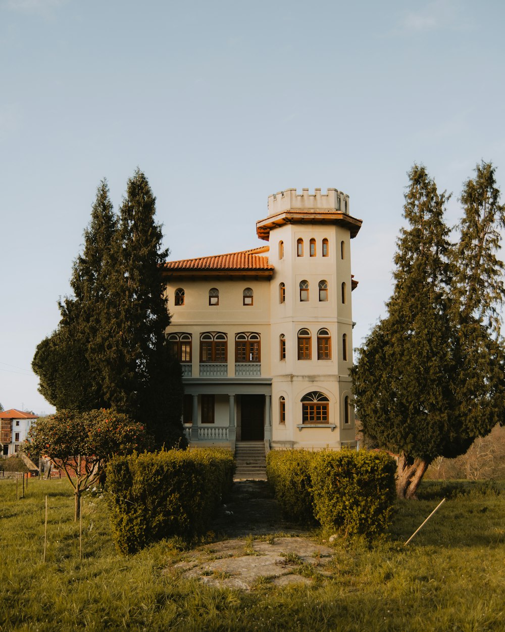 a large white building sitting in the middle of a lush green field