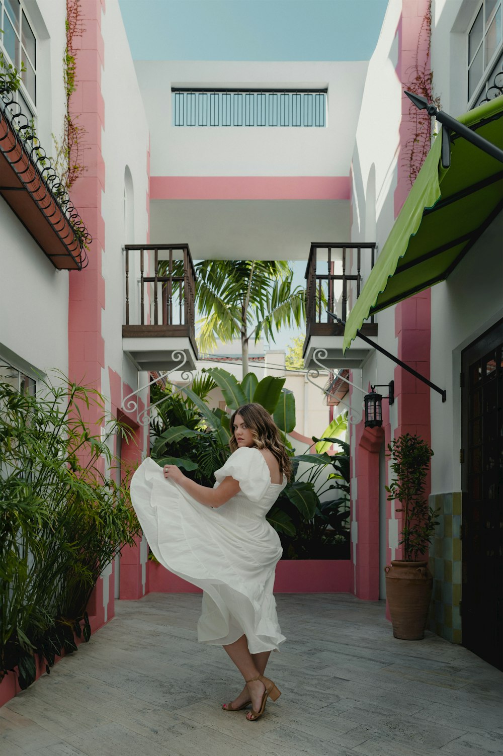 eine Frau in einem weißen Kleid tanzt in einem Innenhof