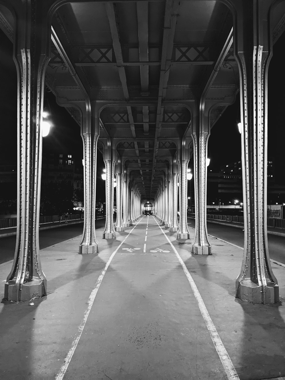 a black and white photo of a street under a bridge