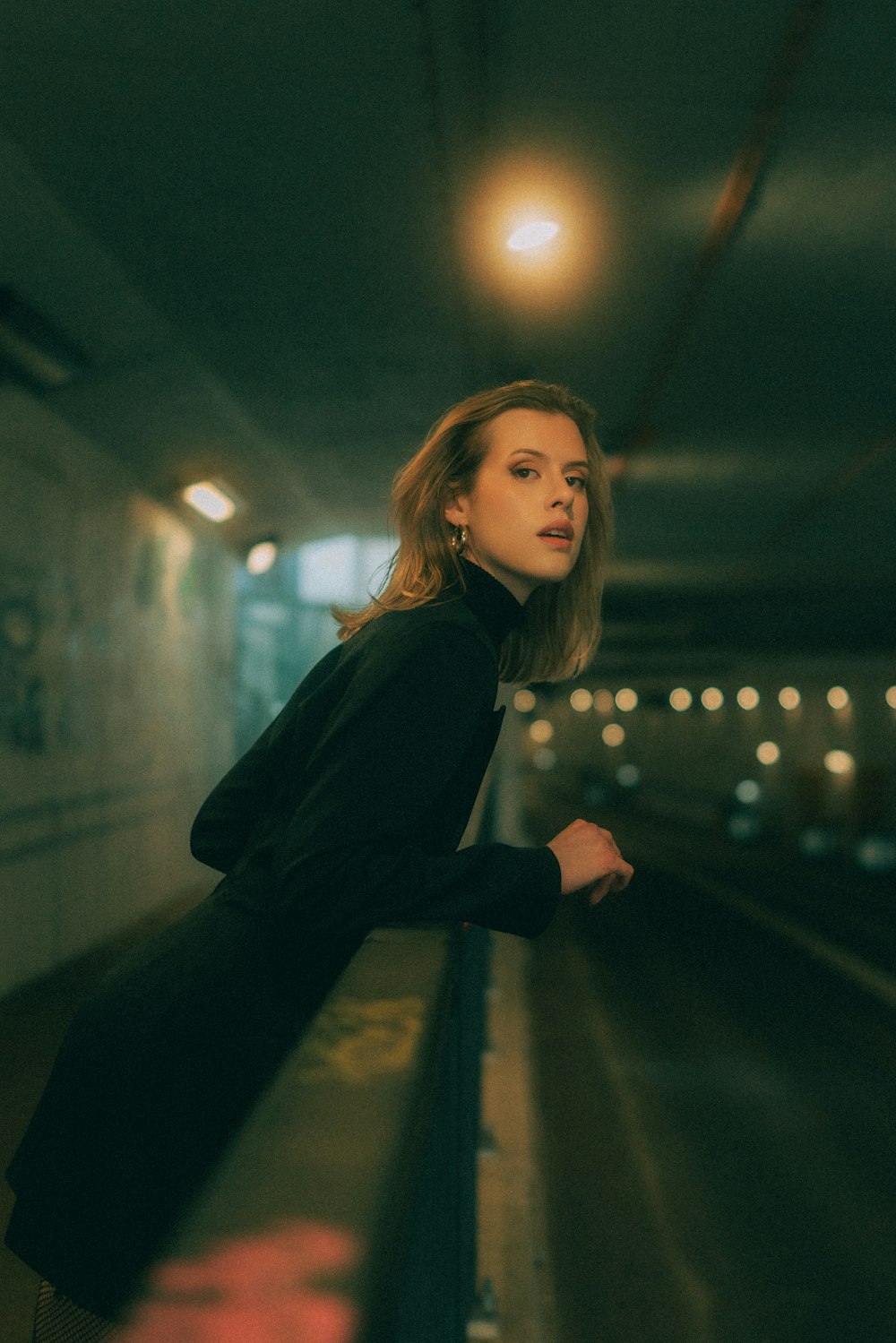 a woman leaning on a rail in a tunnel