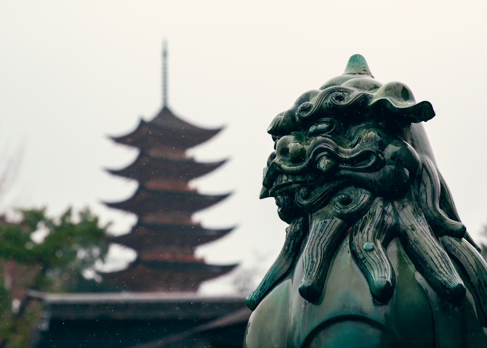 a statue of a lion with a pagoda in the background