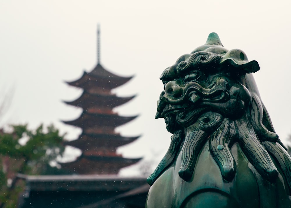 una statua di un leone con una pagoda sullo sfondo