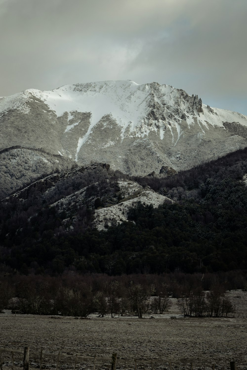 a snow covered mountain range with a fence in the foreground