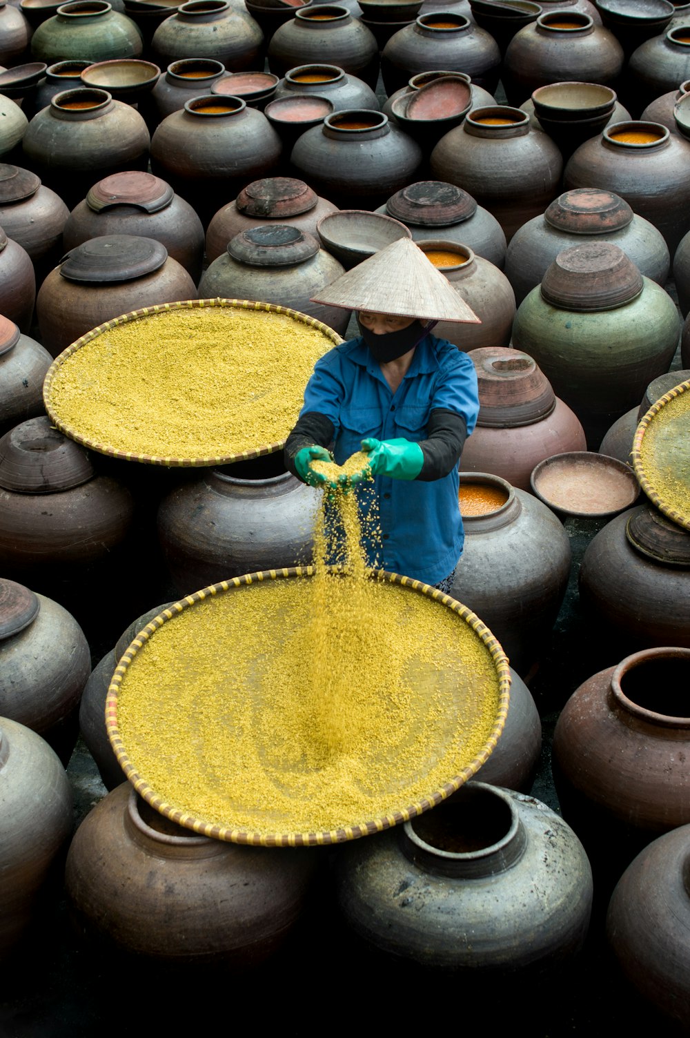 a woman in a blue jacket and a straw hat standing in front of a large