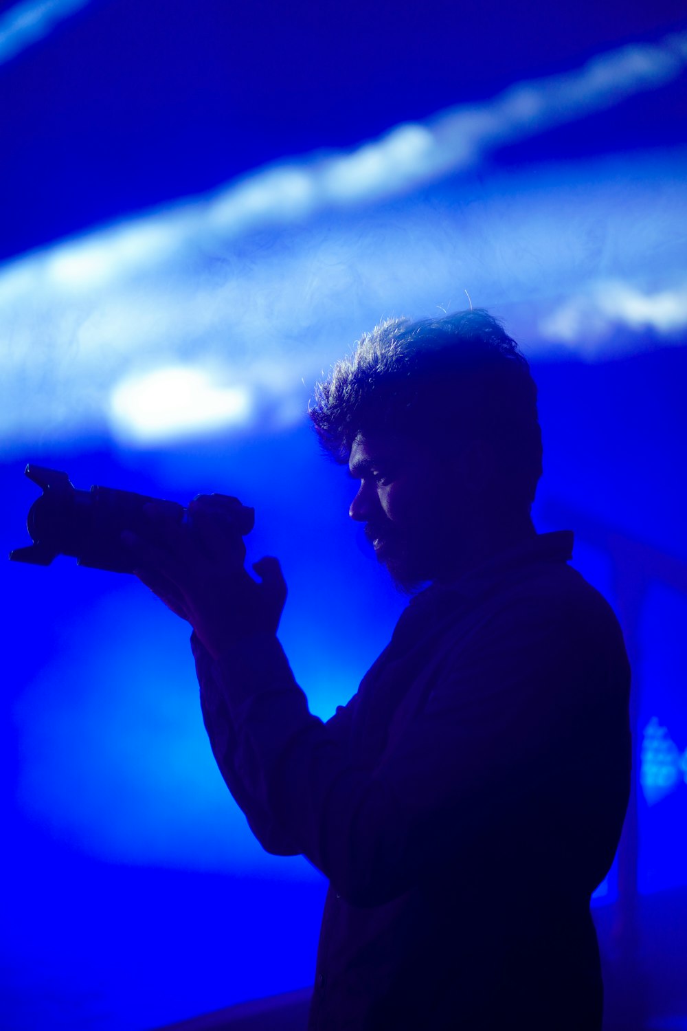 a man standing in front of a blue background holding a cell phone