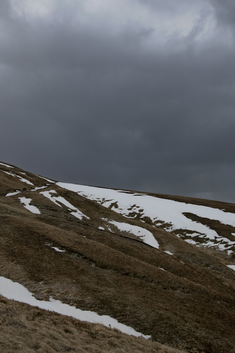 a hill covered in snow under a cloudy sky