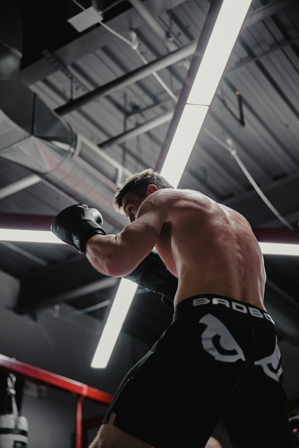 a man standing in a boxing ring holding a black boxing glove