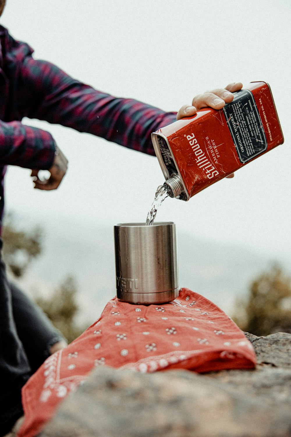 a person pouring water into a can on top of a rock