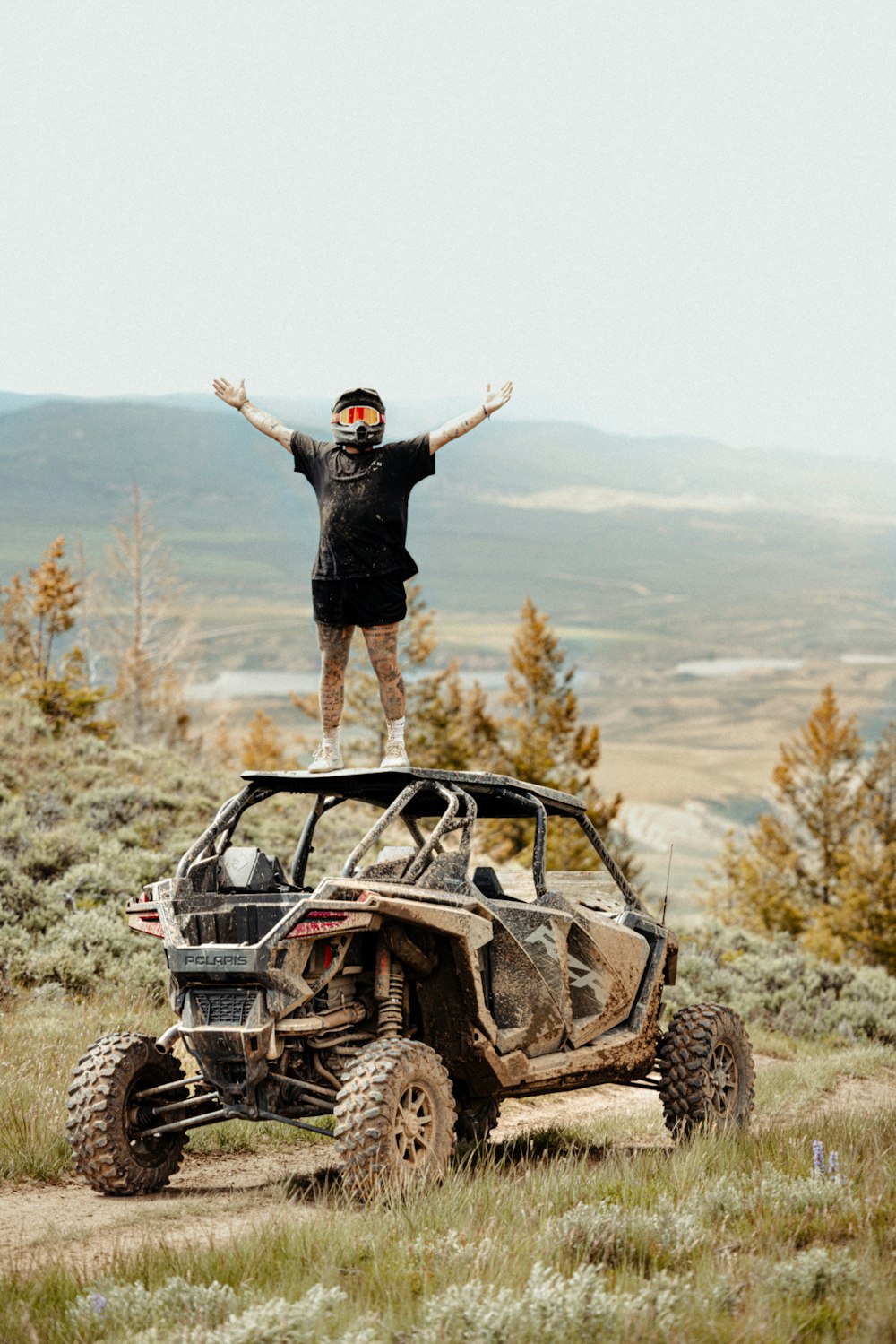 a man standing on top of a vehicle on a dirt road