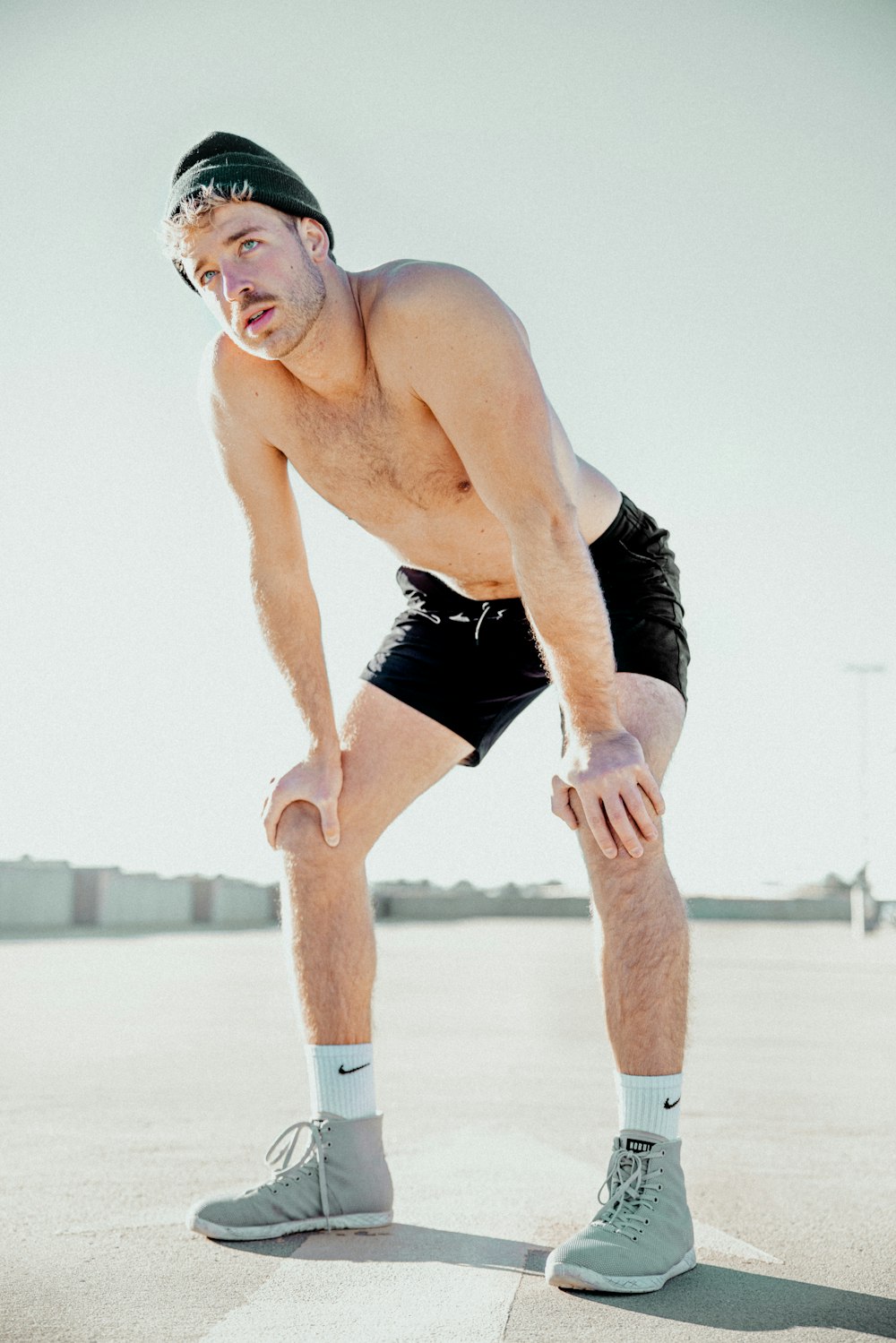 a man with no shirt is standing in a parking lot