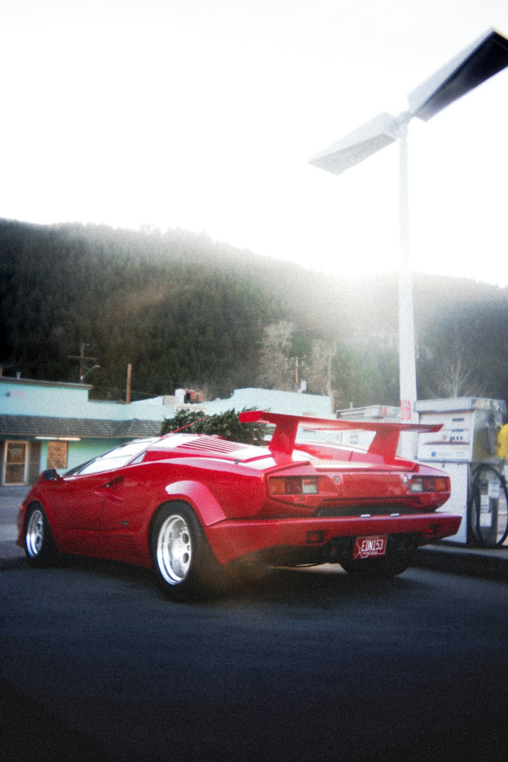 a red sports car parked in front of a gas station