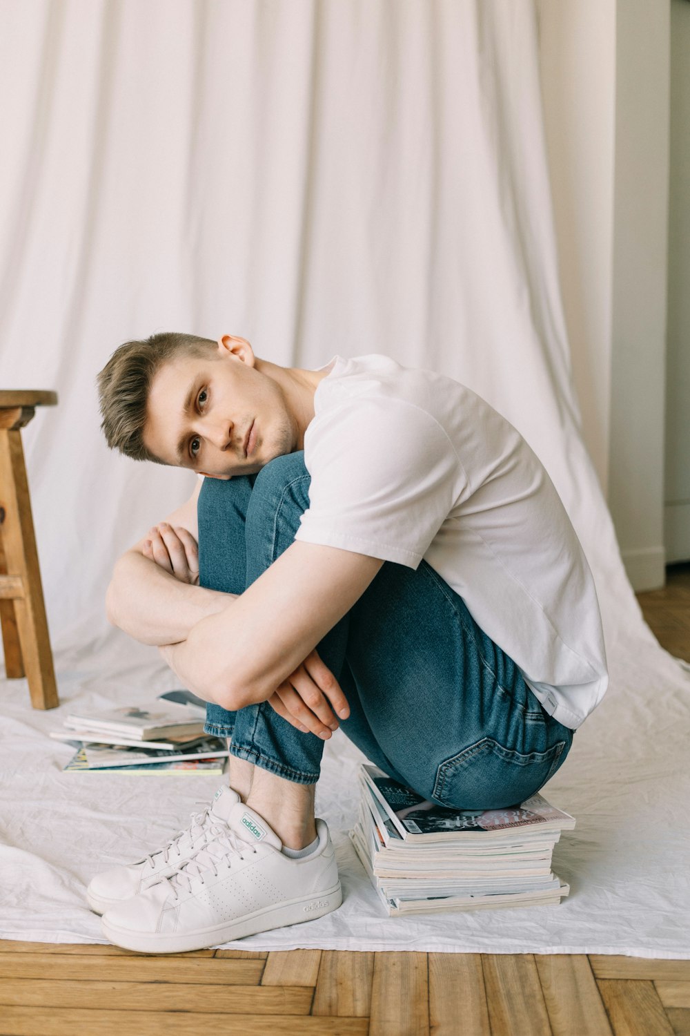 a man sitting on a bed with a stack of books