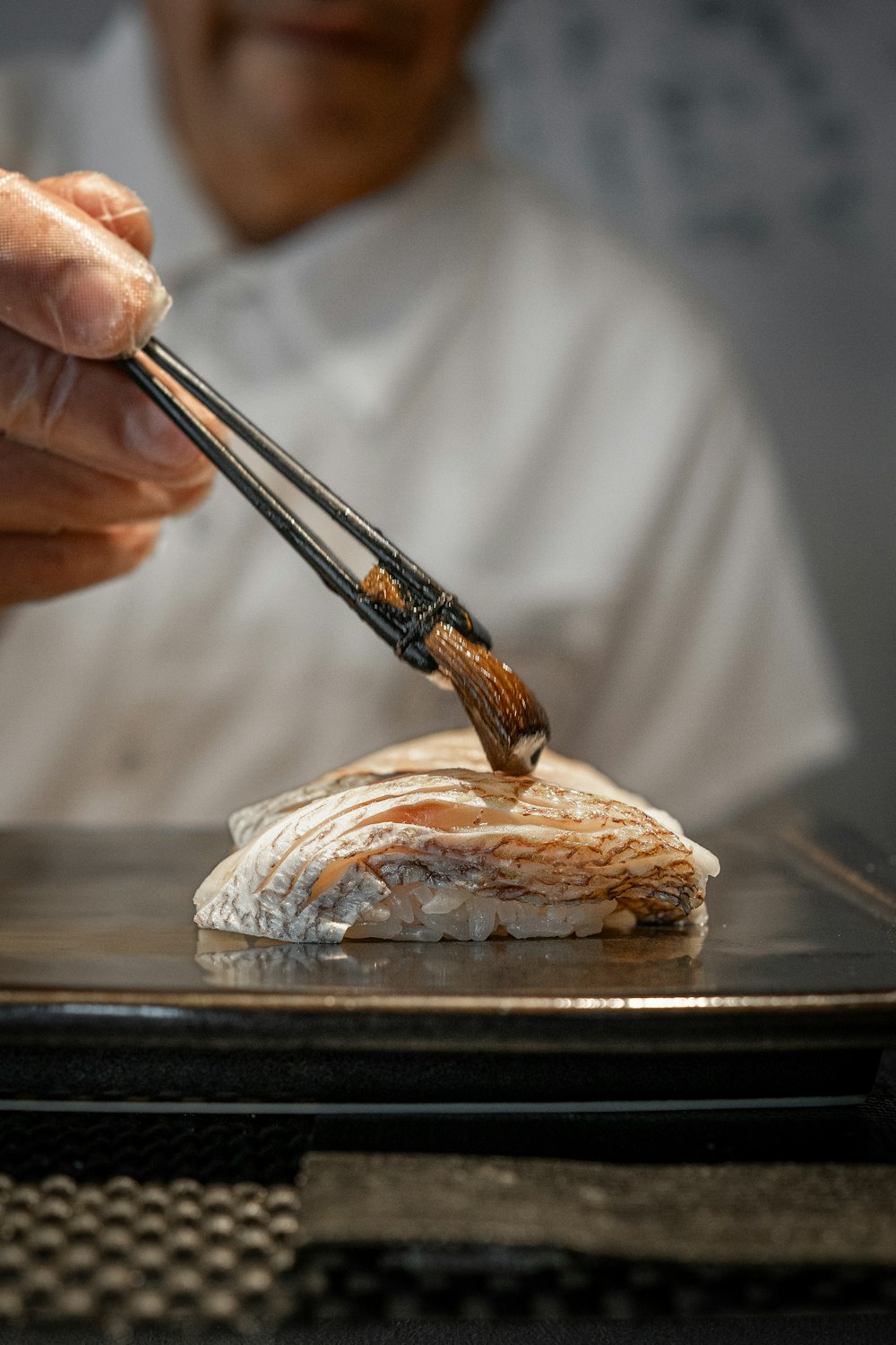 a person holding chopsticks over a piece of food