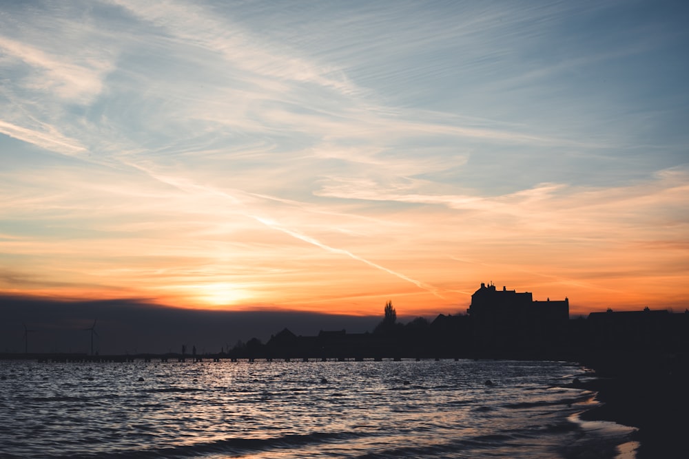 ein Sonnenuntergang über einem Gewässer mit einem Schloss in der Ferne