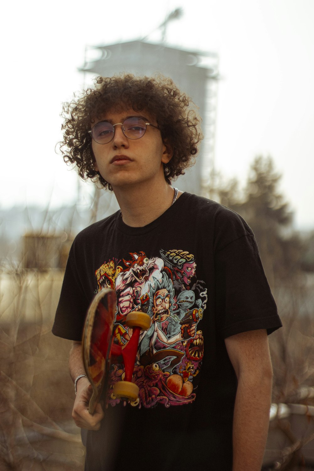 a young man with curly hair holding a skateboard