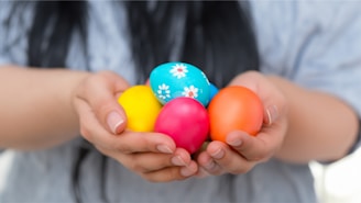 a person holding three colorful eggs in their hands