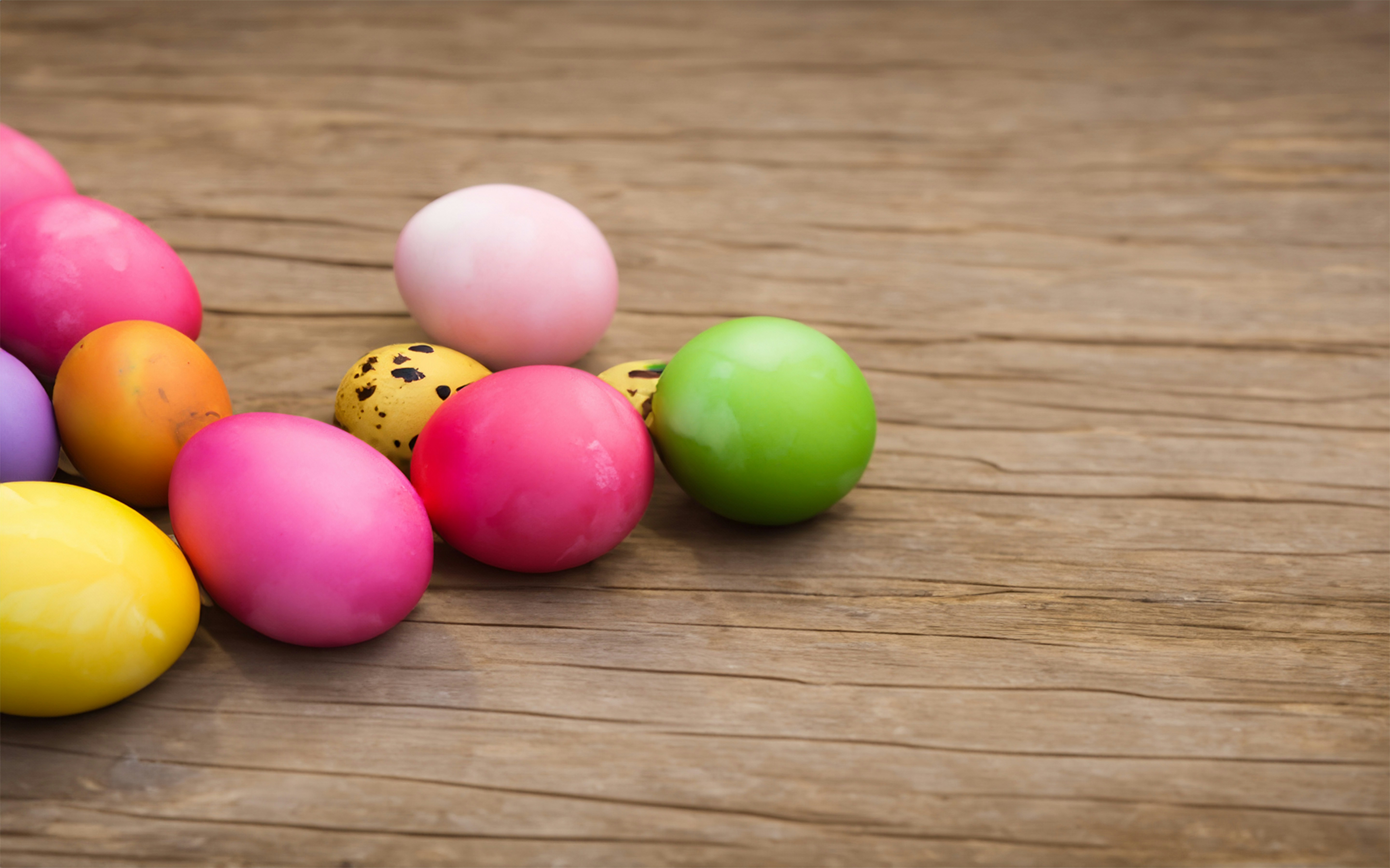 a row of colored eggs sitting on top of a wooden table