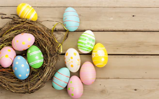 a bird's nest with painted eggs on a wooden surface