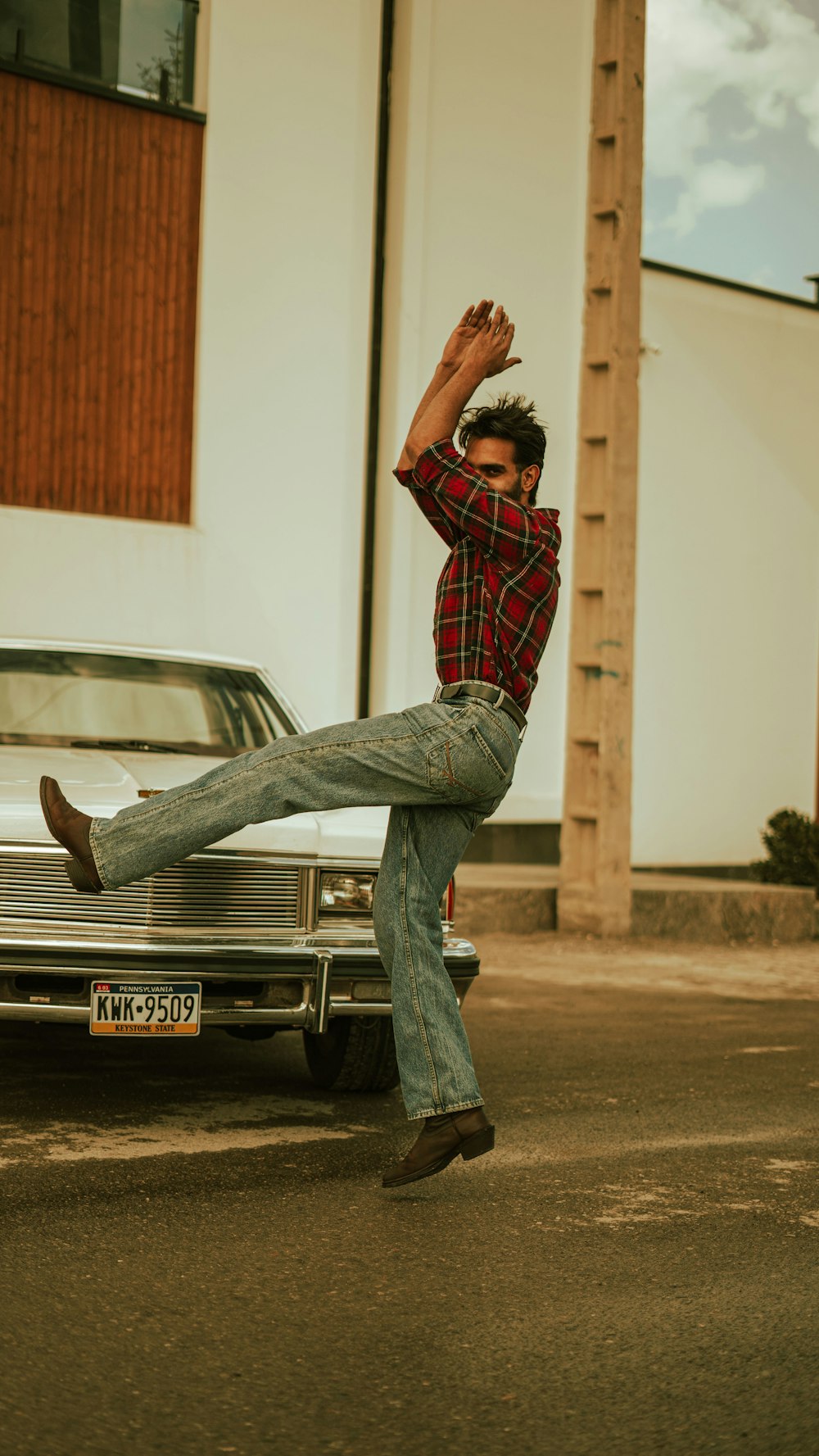 a man in plaid shirt and jeans doing a trick on a skateboard