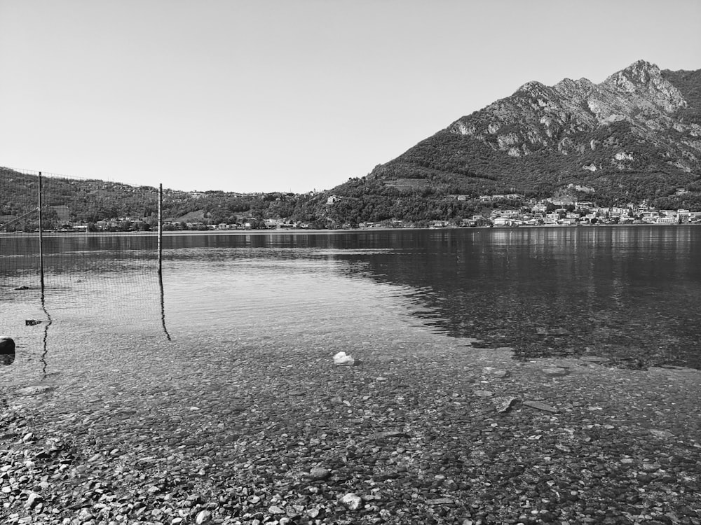 Una foto in bianco e nero di un lago con montagne sullo sfondo