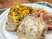 a white plate topped with a burrito and rice