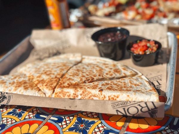 A tray of food on a table with a bowl of salsa
