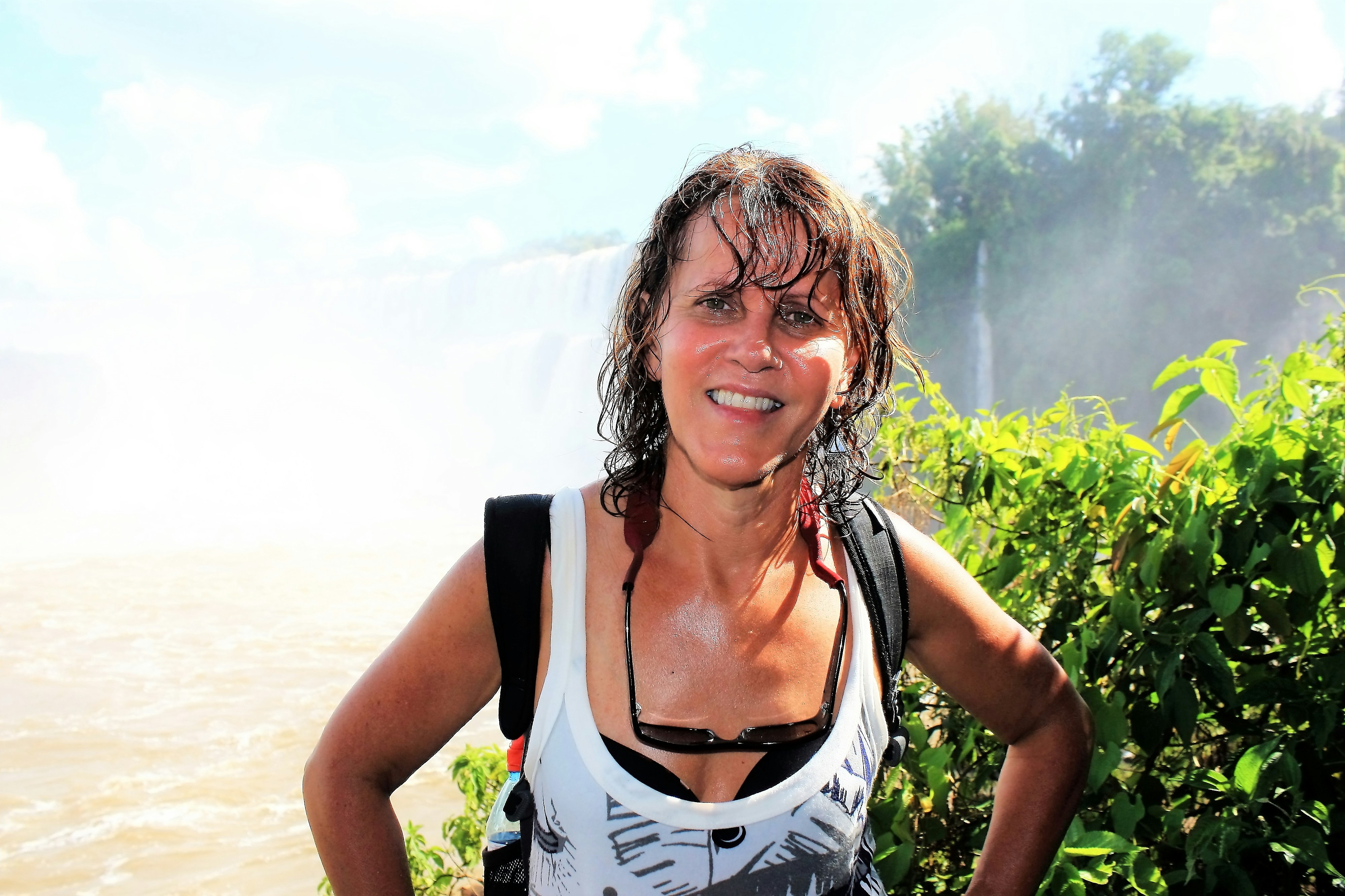 Japanese female traveler with long dark hair smiling outdoors near tropical waterfall setting