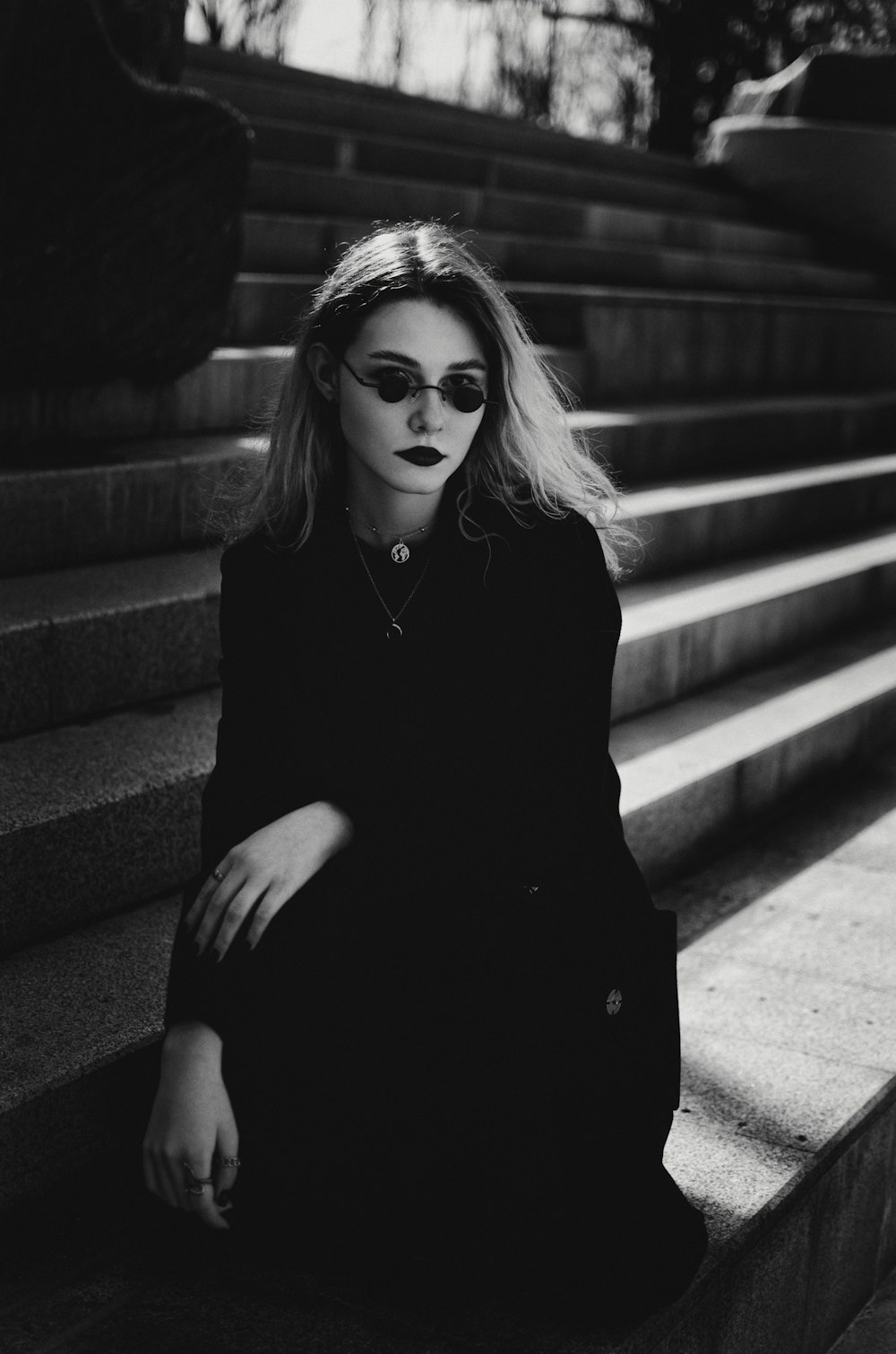 a woman sitting on some steps wearing sunglasses