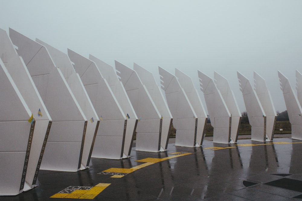 a row of white chairs sitting on top of a wet parking lot