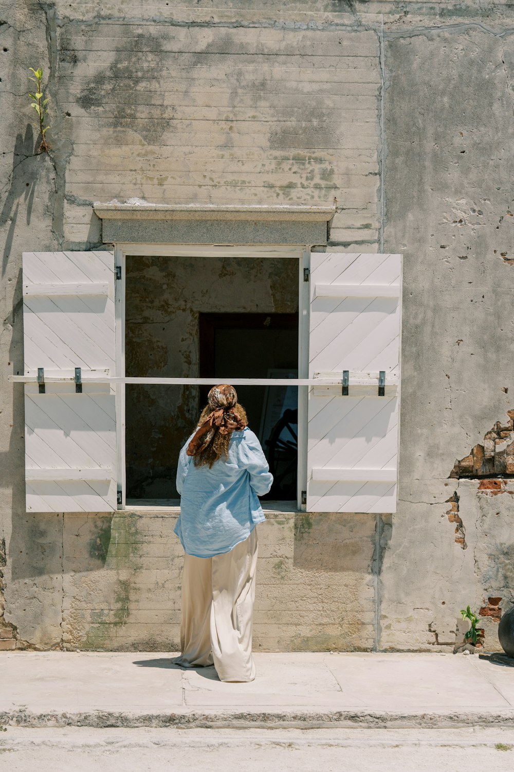 a woman standing in front of a window with shutters open