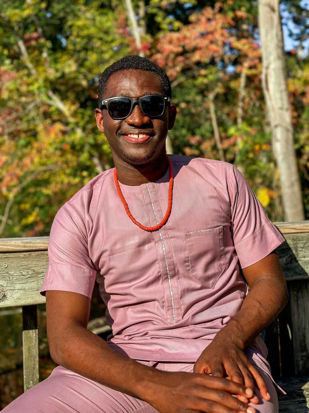 a man sitting on a wooden bench wearing sunglasses