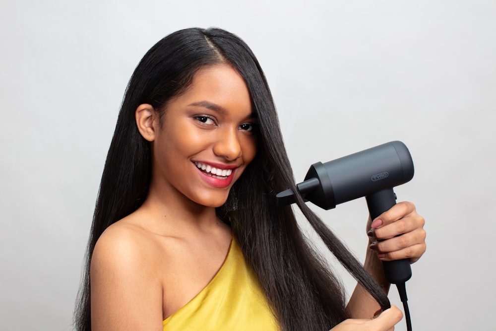 a woman holding a hair dryer and smiling