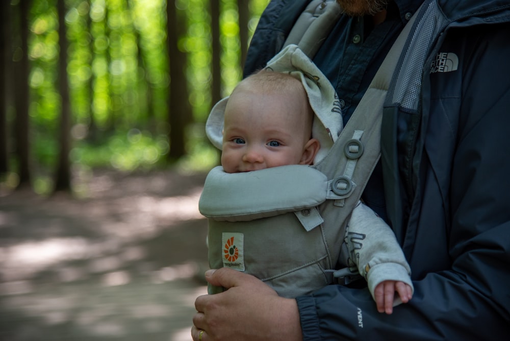 a man carrying a baby in a baby carrier