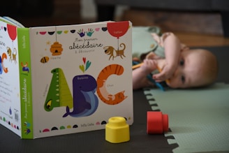 a baby laying on the floor next to a book