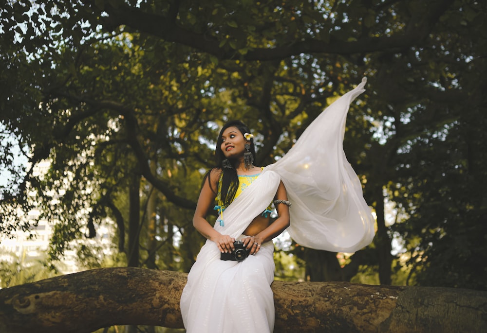 a woman in a white dress standing on a tree branch